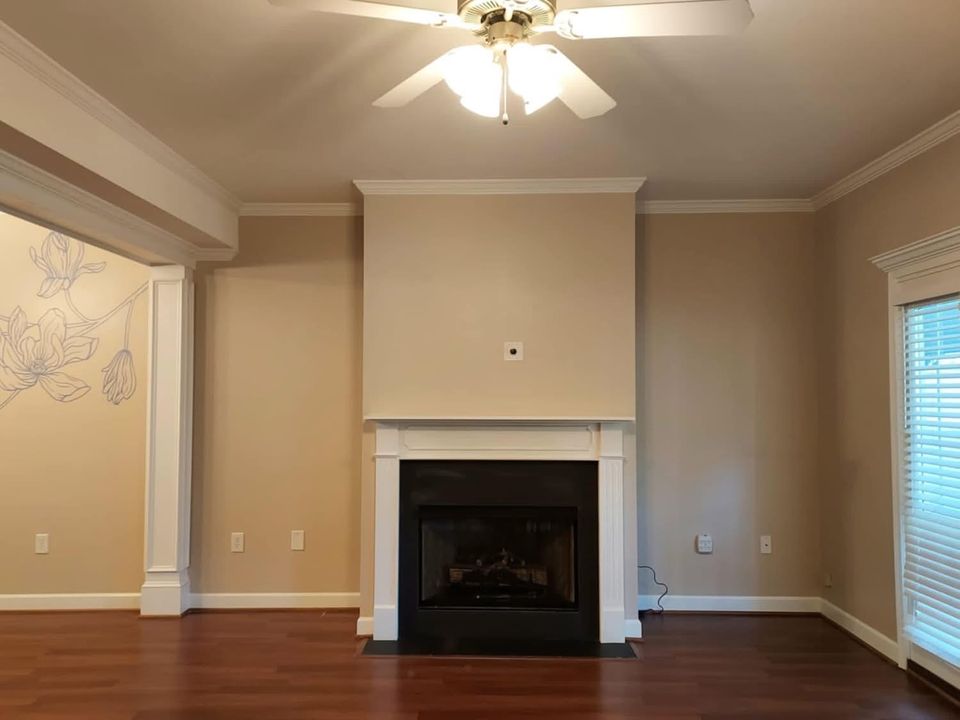 Living room with painted walls, white fireplace mantel, columns and crown molding, with a hand-painted floral line drawing on the side wall, Moore SC